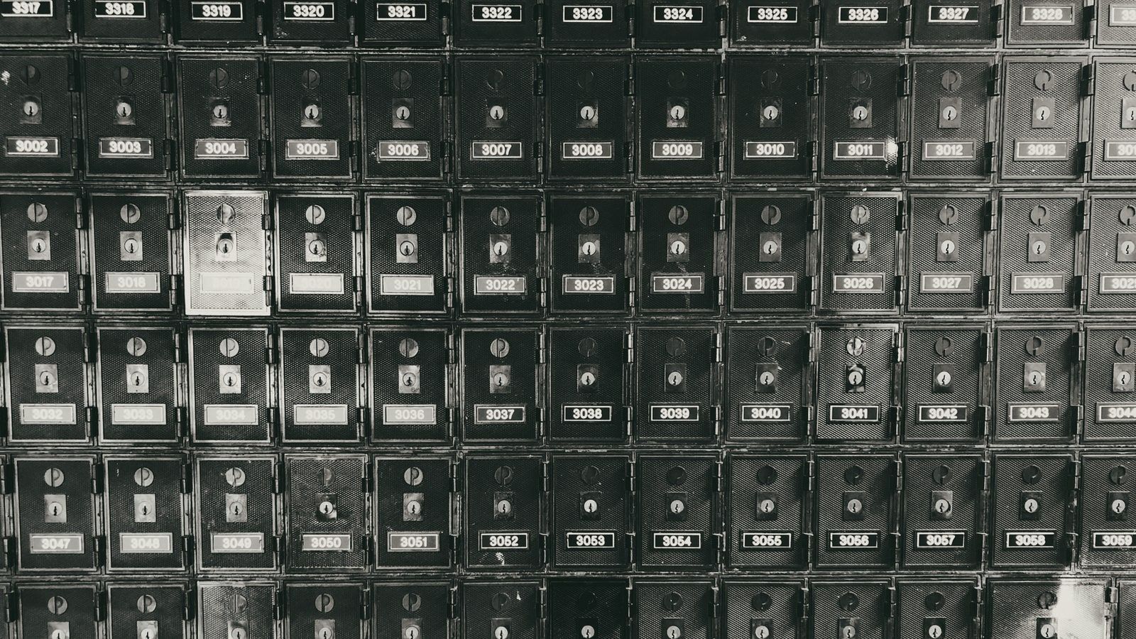 Pared de apartados de correos metálicos numerados, todos iguales, cada uno con su cerradura.