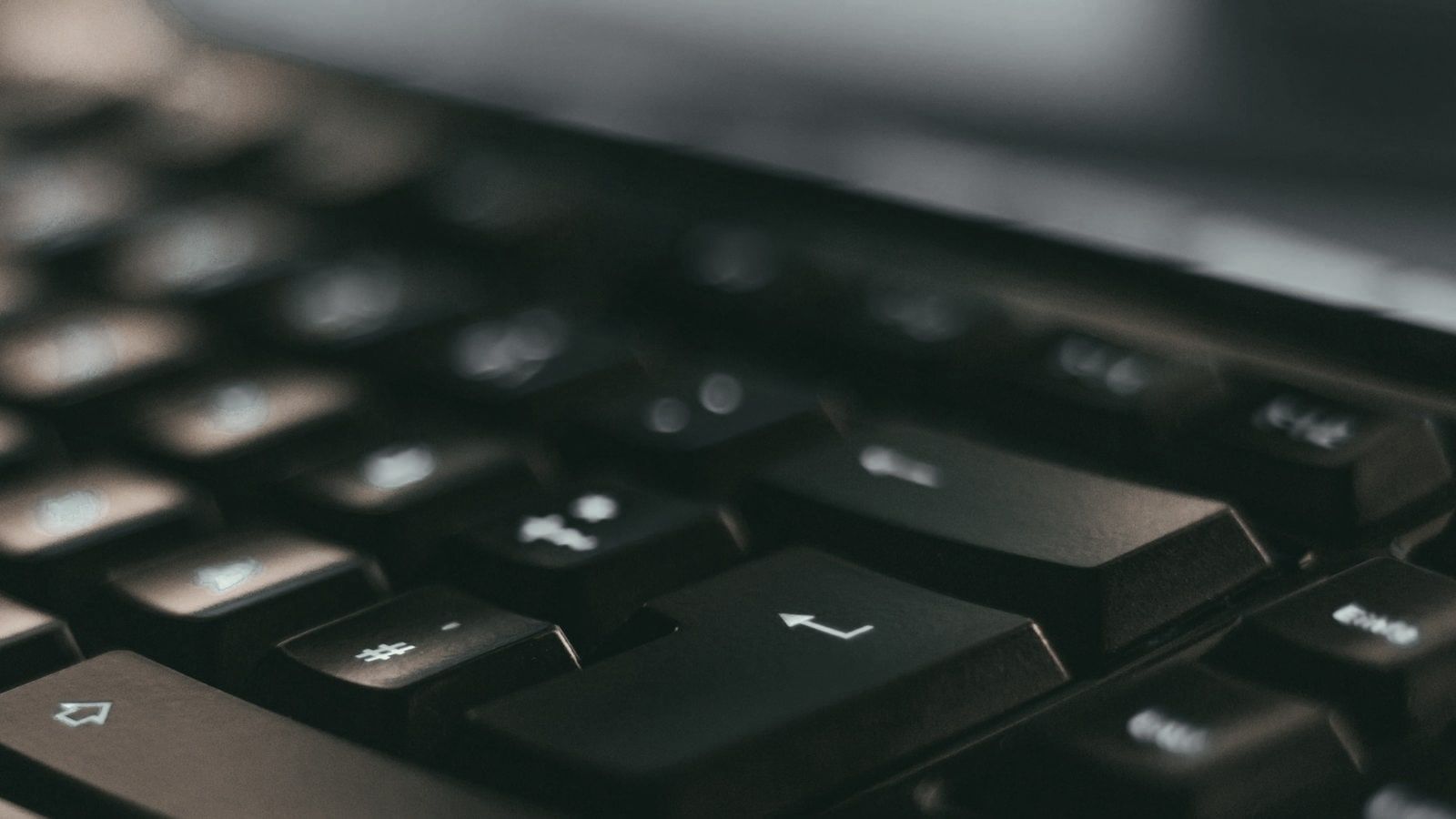 Primer plano de las teclas de un teclado en penumbra, con la tecla Intro en el centro.