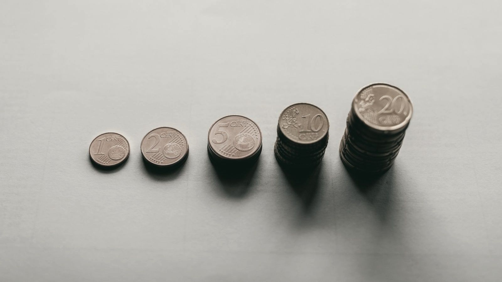 Monedas de céntimo de euro en fila, de una sola moneda a una pila alta, cada vez más altas.